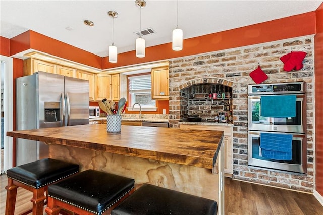 kitchen with pendant lighting, butcher block counters, dark wood-type flooring, and appliances with stainless steel finishes