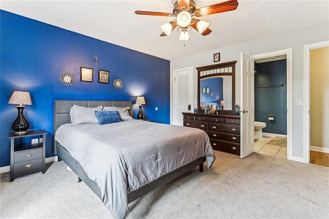 carpeted bedroom with ensuite bathroom, a closet, and ceiling fan