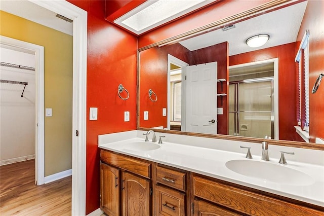 bathroom featuring a skylight, hardwood / wood-style floors, vanity, and a shower with shower door