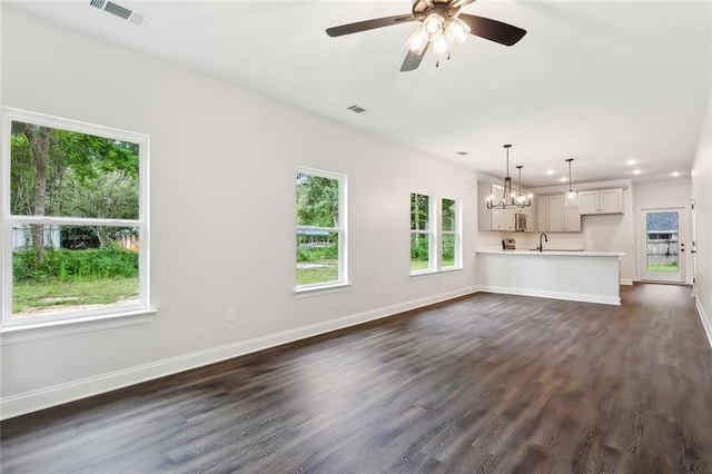 unfurnished living room featuring dark wood-type flooring and ceiling fan with notable chandelier