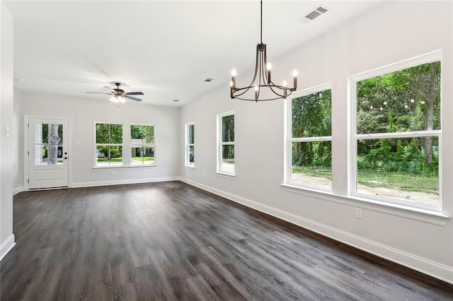 unfurnished dining area featuring dark hardwood / wood-style flooring, a healthy amount of sunlight, and ceiling fan with notable chandelier