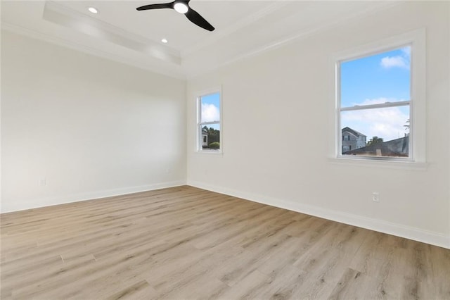 empty room with light hardwood / wood-style floors, a raised ceiling, ceiling fan, and ornamental molding