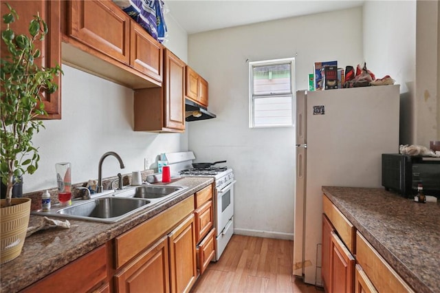 kitchen with light wood-type flooring, white appliances, and sink