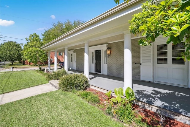 view of exterior entry with a yard and a porch