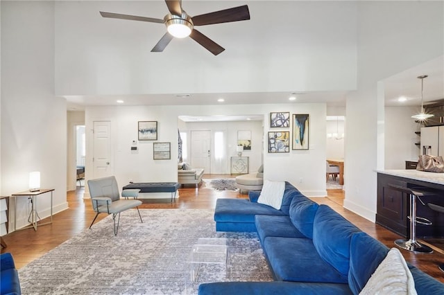 living room featuring a towering ceiling, hardwood / wood-style flooring, and ceiling fan