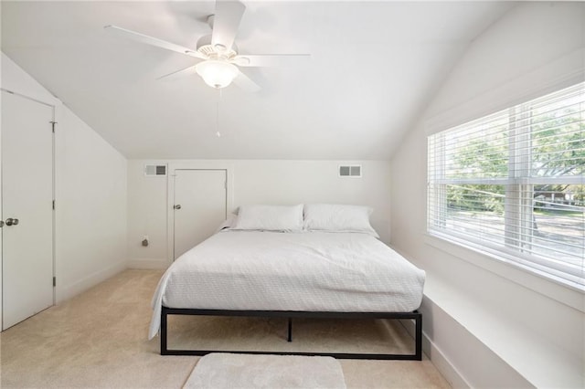 bedroom with ceiling fan, light colored carpet, and vaulted ceiling