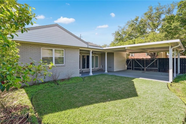 rear view of property with a lawn and a carport