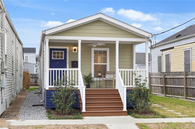 shotgun-style home featuring a porch, fence, and a ceiling fan