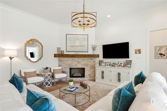 living room featuring crown molding, a fireplace, wood-type flooring, and an inviting chandelier