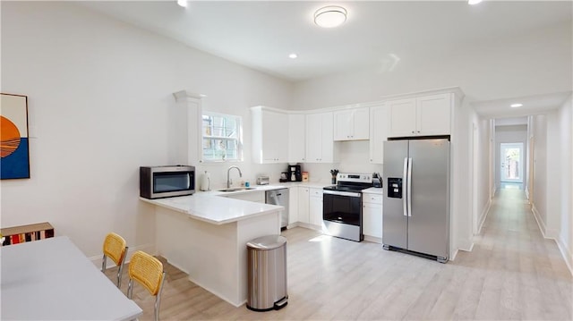 kitchen with kitchen peninsula, sink, white cabinets, and stainless steel appliances