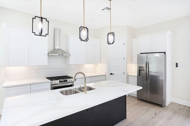 kitchen with stainless steel appliances, sink, white cabinetry, wall chimney range hood, and pendant lighting