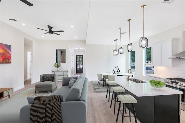 living room with sink, ceiling fan, and light wood-type flooring