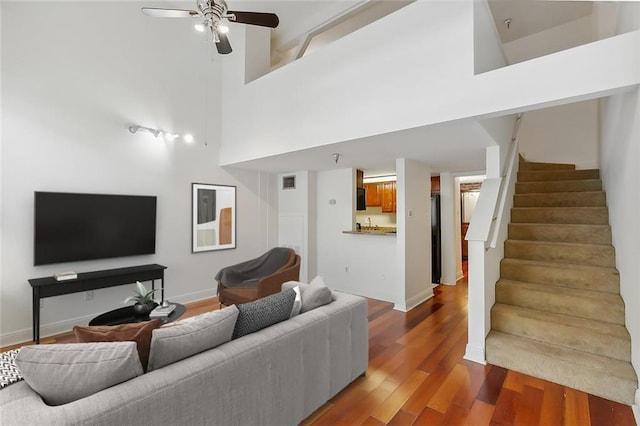 living room with hardwood / wood-style flooring, ceiling fan, and a high ceiling