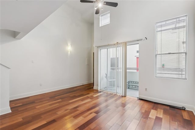 unfurnished room with hardwood / wood-style flooring, ceiling fan, a healthy amount of sunlight, and a high ceiling