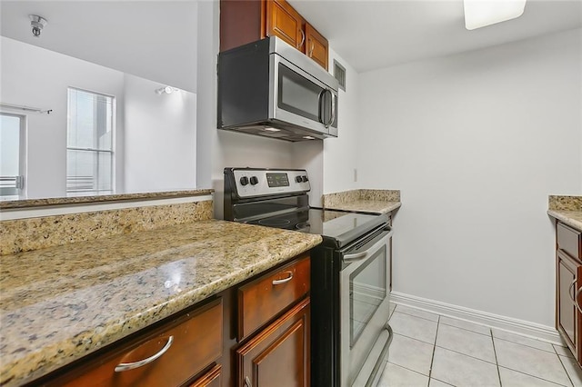 kitchen featuring light tile patterned floors, stainless steel appliances, and light stone counters