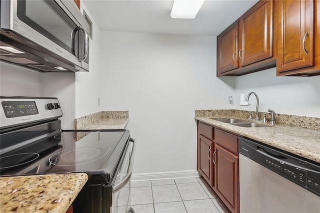 kitchen with light stone countertops, sink, light tile patterned floors, and stainless steel appliances