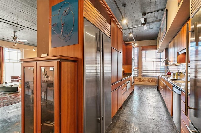 kitchen featuring ceiling fan, wooden walls, and appliances with stainless steel finishes