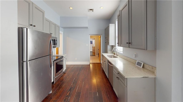 kitchen with visible vents, dark wood finished floors, gray cabinets, appliances with stainless steel finishes, and a sink