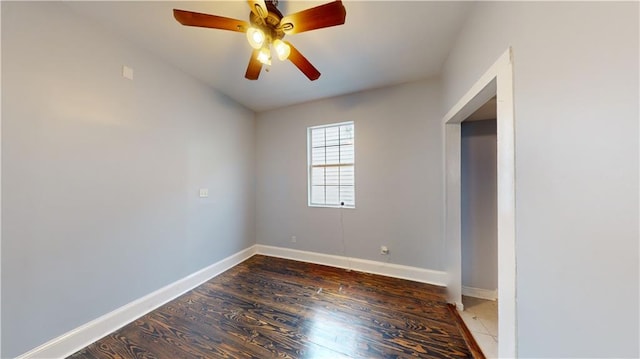 spare room featuring baseboards, wood finished floors, and a ceiling fan
