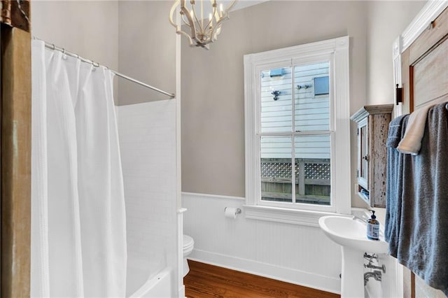 bathroom featuring hardwood / wood-style floors, a notable chandelier, toilet, and shower / bath combo