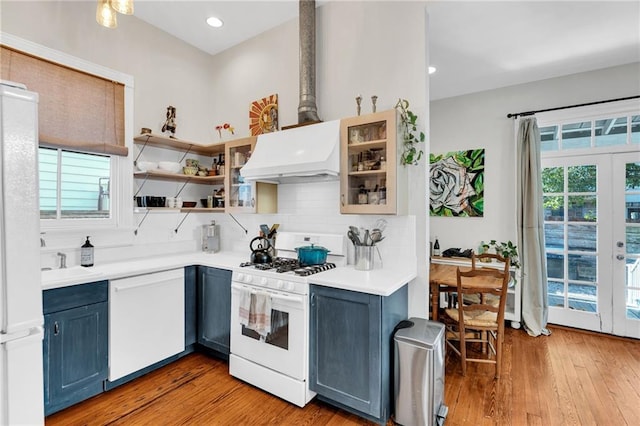 kitchen featuring blue cabinetry, french doors, tasteful backsplash, white appliances, and custom range hood