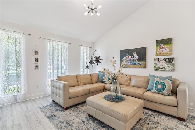 living room featuring lofted ceiling, baseboards, a notable chandelier, and light wood finished floors