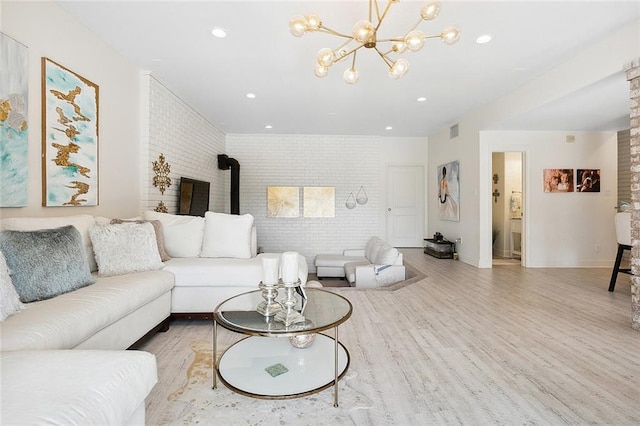 living area with recessed lighting, light wood-style flooring, a wood stove, brick wall, and a chandelier