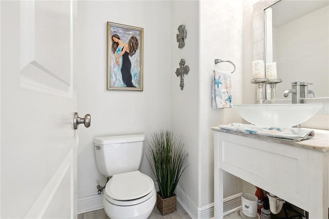 half bathroom featuring vanity, toilet, and baseboards