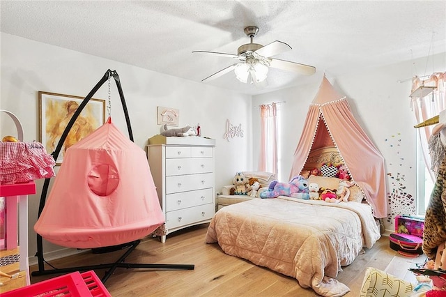 bedroom featuring a textured ceiling, light wood-type flooring, and a ceiling fan