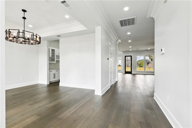 hallway with a notable chandelier, ornamental molding, and dark wood-type flooring