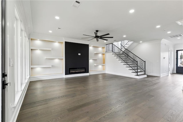 unfurnished living room featuring dark hardwood / wood-style flooring, a large fireplace, ceiling fan, and ornamental molding