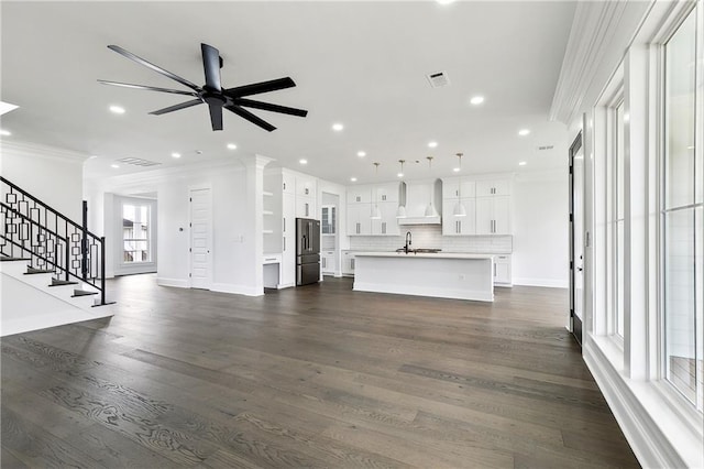 unfurnished living room with crown molding, ceiling fan, dark wood-type flooring, and sink