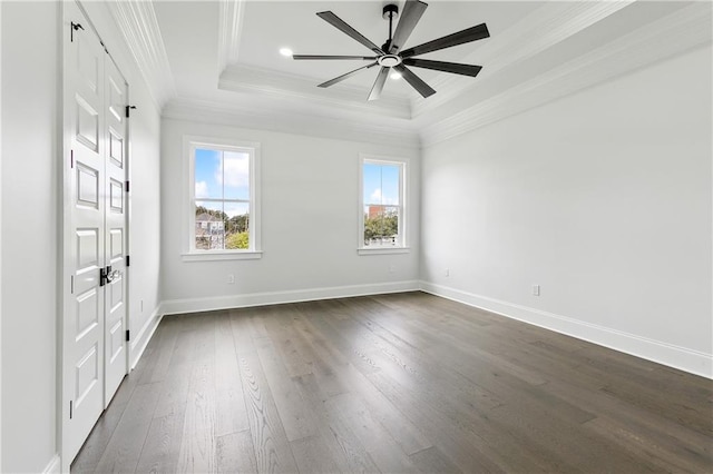 empty room with dark hardwood / wood-style flooring, a raised ceiling, ceiling fan, and ornamental molding