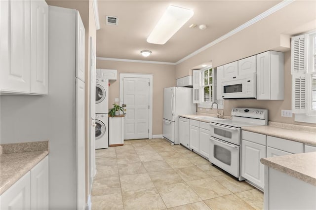 kitchen featuring white appliances, white cabinetry, stacked washer / drying machine, sink, and crown molding