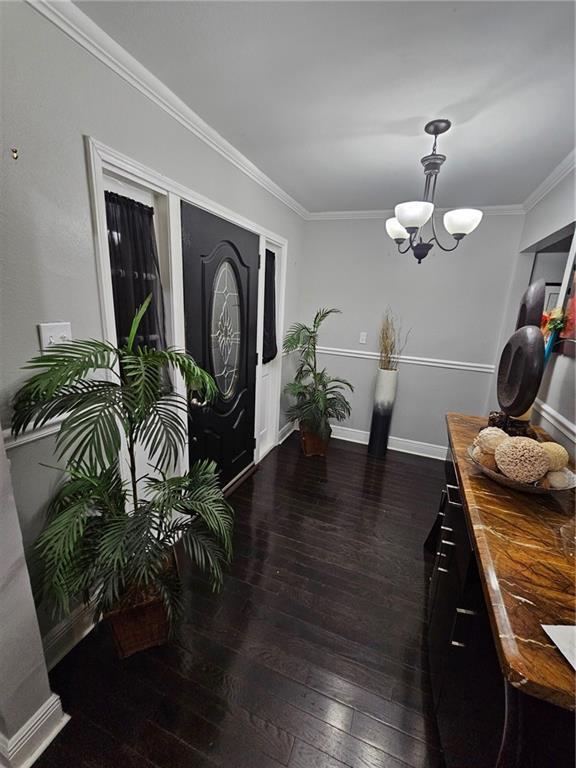 entrance foyer with crown molding, dark hardwood / wood-style flooring, and a notable chandelier