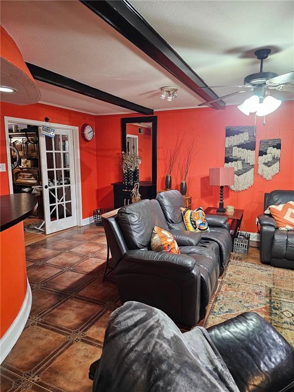 living room featuring beamed ceiling and ceiling fan