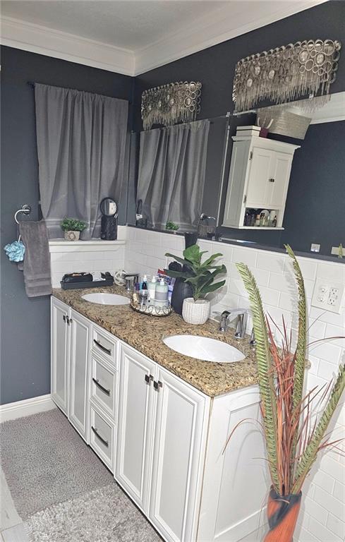 bathroom with decorative backsplash, crown molding, and vanity