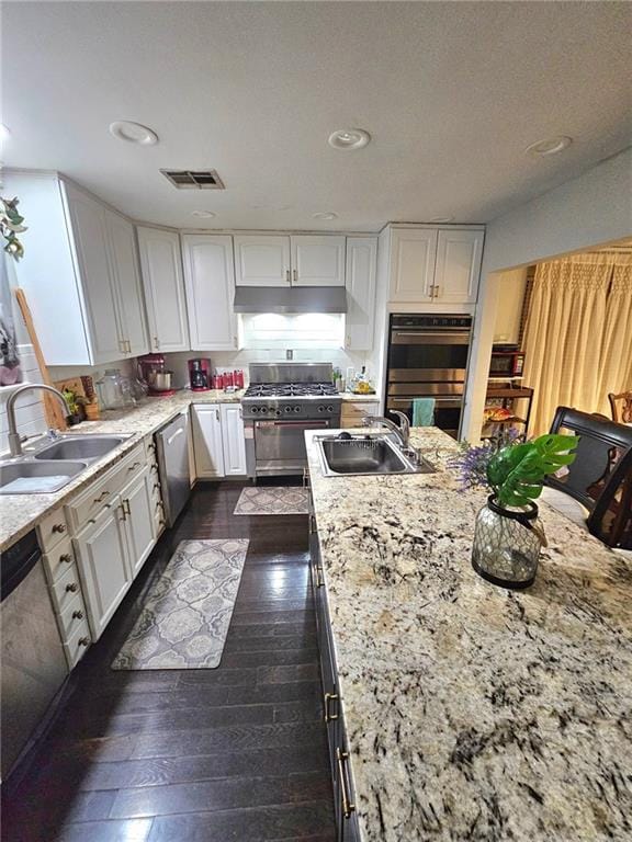 kitchen with dark hardwood / wood-style floors, sink, white cabinetry, and stainless steel appliances