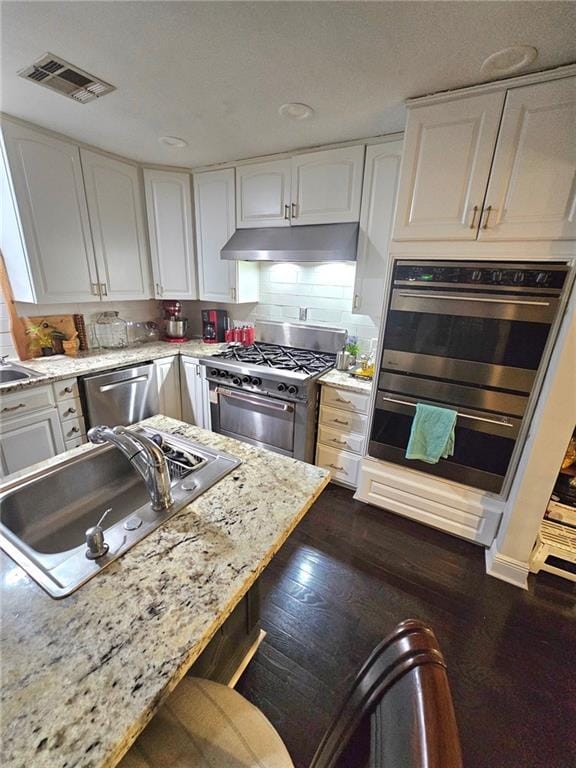 kitchen featuring white cabinets, appliances with stainless steel finishes, light stone countertops, and sink