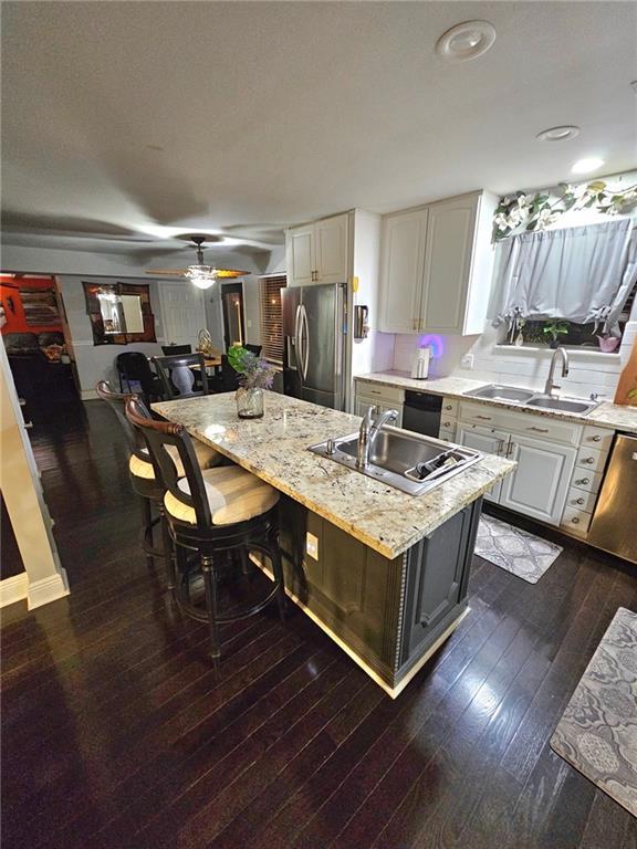 kitchen with a breakfast bar, white cabinetry, stainless steel appliances, and an island with sink