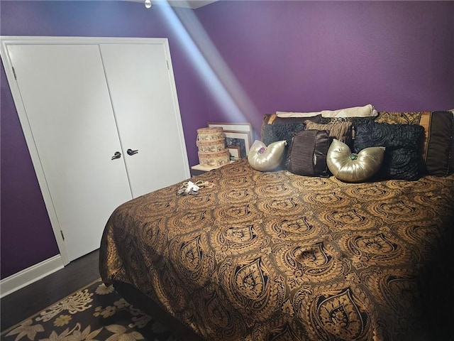 bedroom with dark hardwood / wood-style floors and a closet