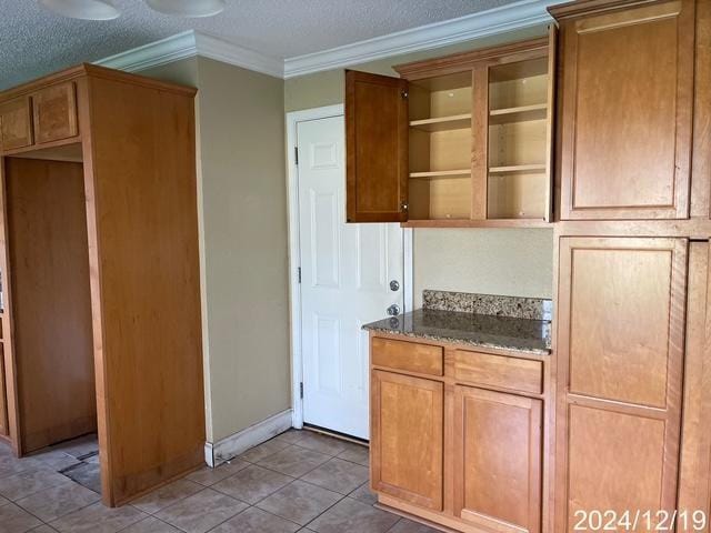 1809 W Frisco Dr, La Place, LA 70068 - kitchen with dark stone countertops, light tile patterned flooring, a textured ceiling, and ornamental molding
