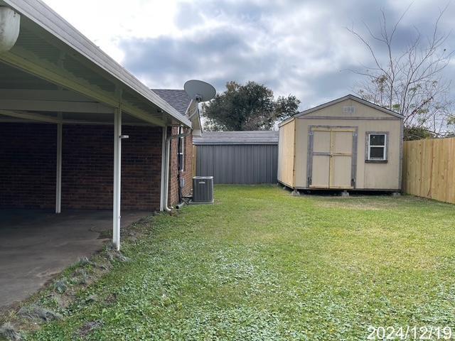 1809 W Frisco Dr, La Place, LA 70068 - view of yard with central AC, a carport, and a storage unit