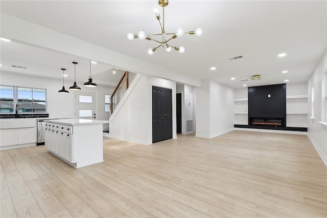 kitchen featuring white cabinets, decorative light fixtures, light wood-type flooring, and a kitchen island with sink