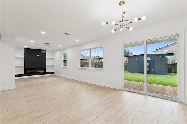 unfurnished living room with a notable chandelier and light wood-type flooring