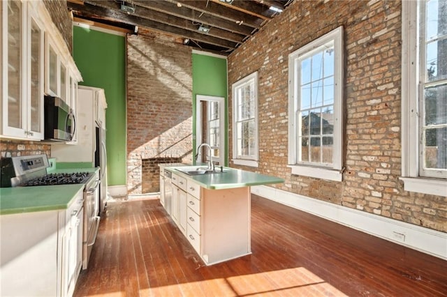 1432 Magazine St, New Orleans, LA 70130 - kitchen with a center island with sink, white cabinets, sink, stainless steel appliances, and brick wall