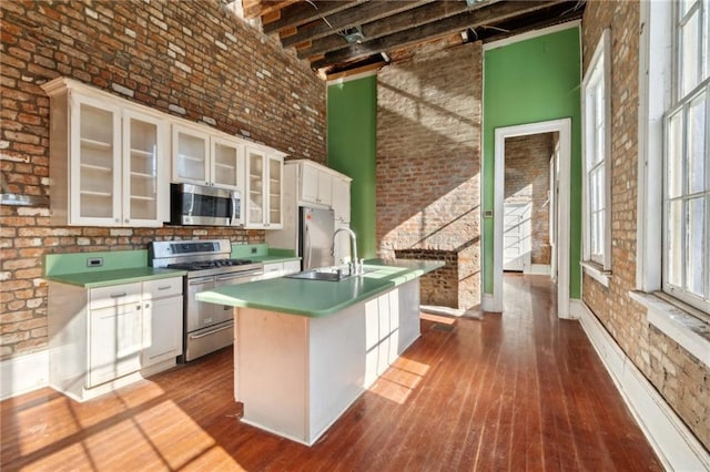 1432 Magazine St, New Orleans, LA 70130 - kitchen with brick wall, white cabinetry, stainless steel appliances, and a high ceiling