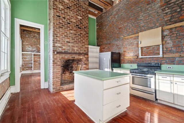 1432 Magazine St, New Orleans, LA 70130 - kitchen with a kitchen island, white cabinetry, stainless steel appliances, and a high ceiling