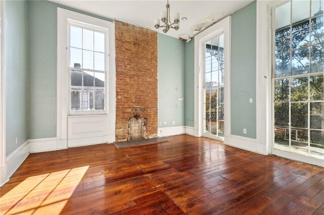 1432 Magazine St, New Orleans, LA 70130 - unfurnished living room with plenty of natural light, wood-type flooring, a fireplace, and an inviting chandelier