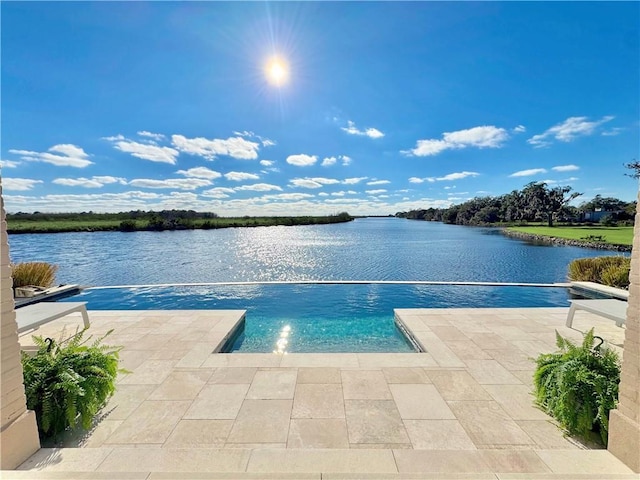 view of swimming pool featuring a patio and a water view